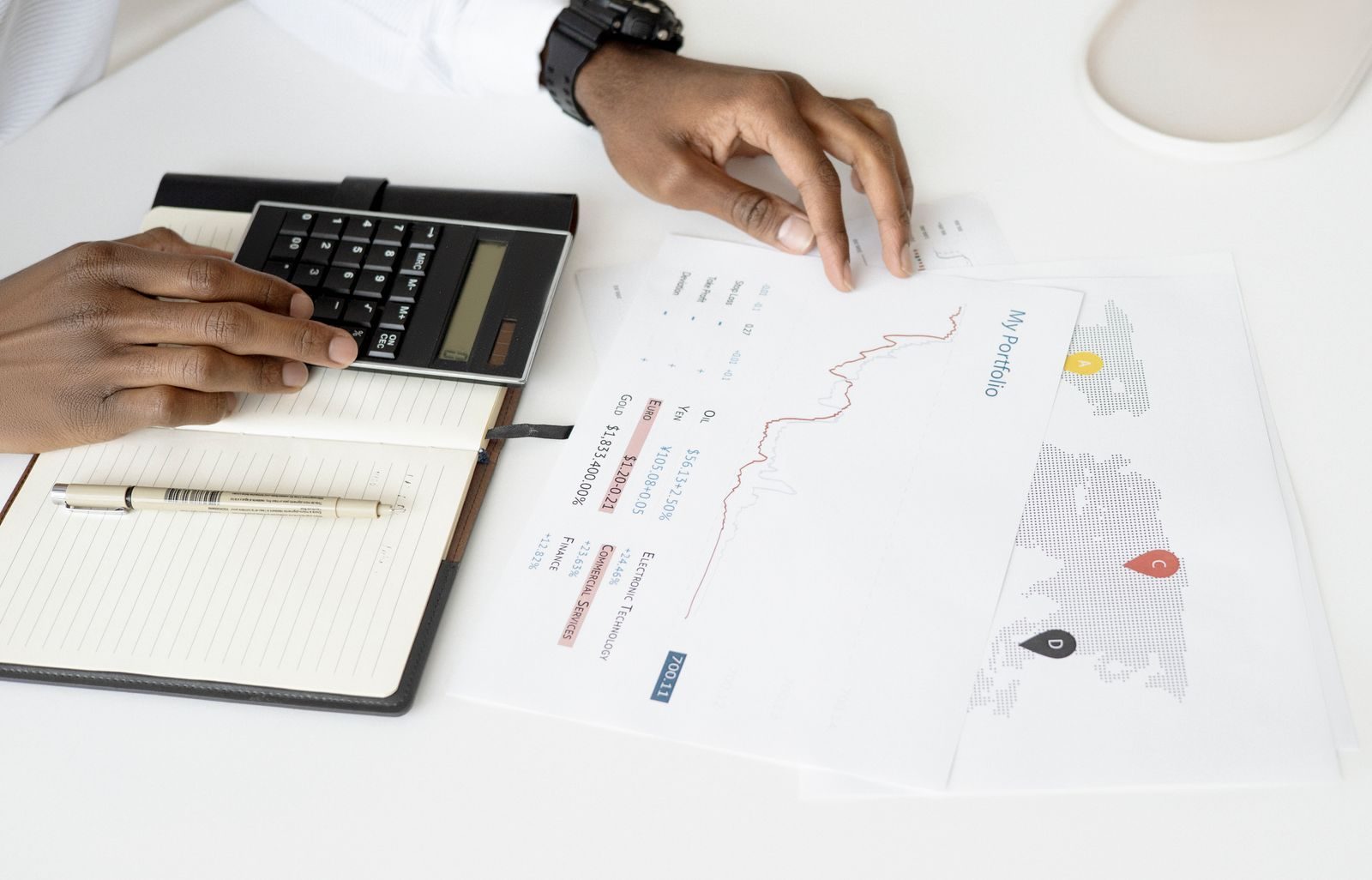 Hands holding a calculator beside a printed portfolio report and a world map marked with location pins.